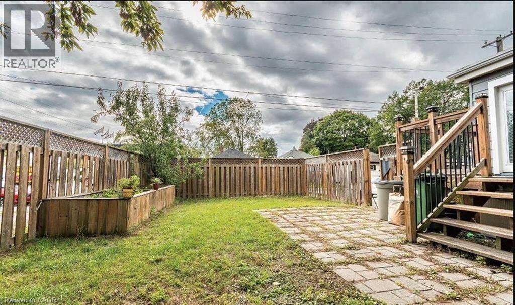 Private backyard featuring a wood privacy fence, a raised planter bed, and a stone paver patio - 63 Audrey Street, Hamilton, ON - Outdoor