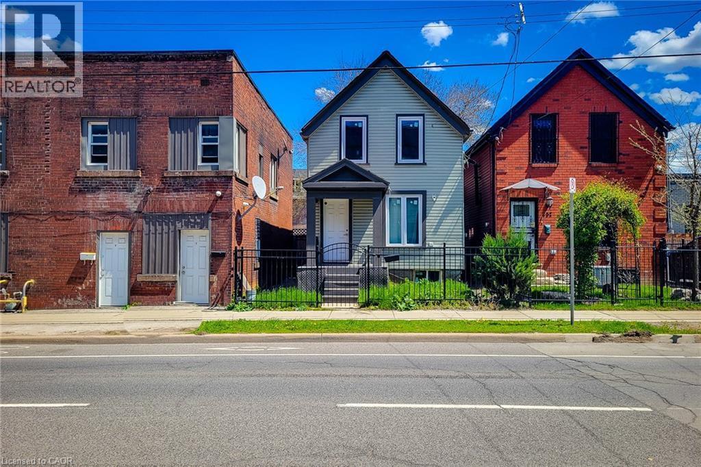Gabled residence featuring light-colored siding, contrasting dark trim, and a covered front entry - 334 Gage Avenue N, Hamilton, ON - Outdoor With Facade
