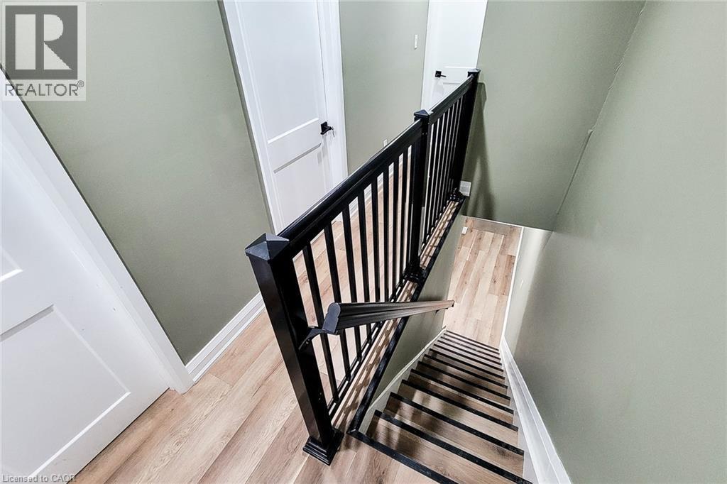 Stairwell featuring modern black railings, light wood-finish flooring, and light green wall paint - 334 Gage Avenue N, Hamilton, ON - Indoor Photo Showing Other Room