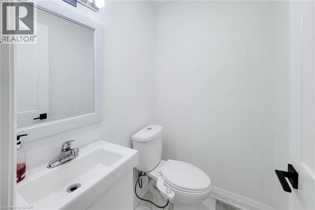 Compact bathroom featuring a wall-mounted sink with chrome faucet, framed mirror, and contemporary lighting fixture - 334 Gage Avenue N, Hamilton, ON - Indoor Photo Showing Bathroom
