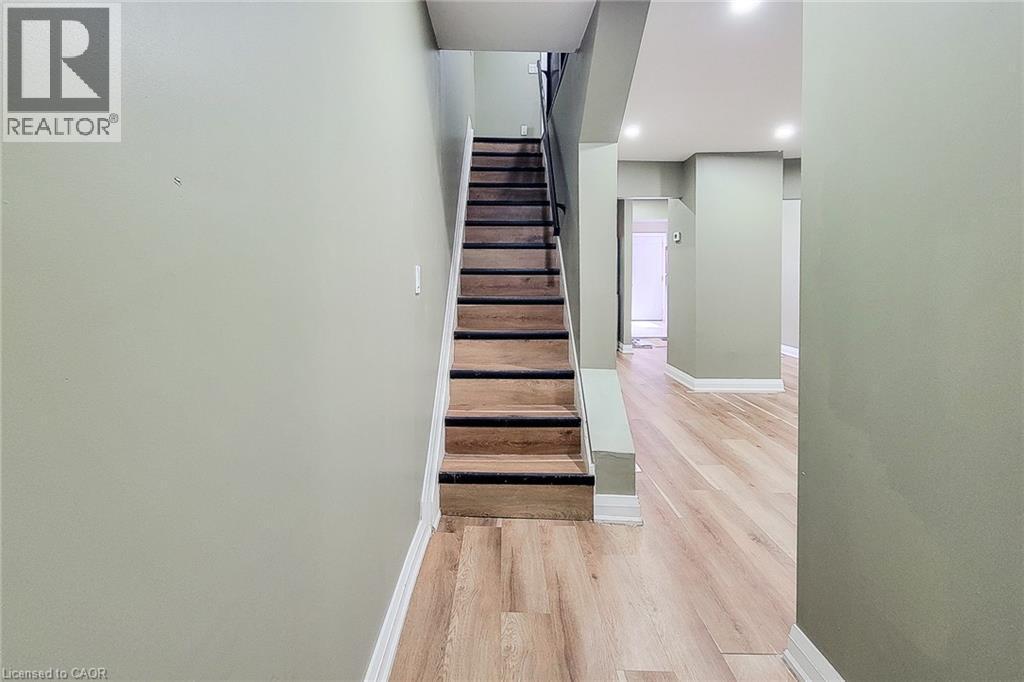 Interior staircase with wood-finish treads and risers, complemented by a black handrail and white trim - 334 Gage Avenue N, Hamilton, ON - Indoor Photo Showing Other Room