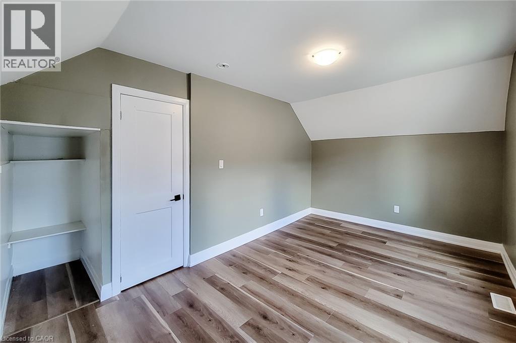 Room featuring wood-finish flooring, two-tone painted walls, and a built-in shelving unit - 334 Gage Avenue N, Hamilton, ON - Indoor Photo Showing Other Room