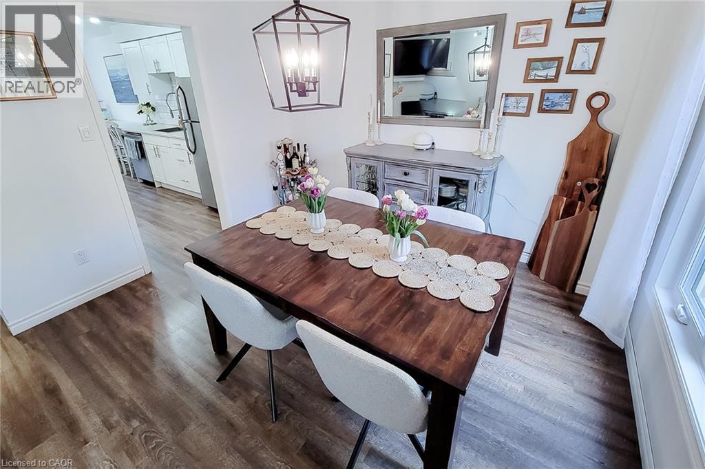 Formal dining area featuring wood-finish flooring, a contemporary black geometric chandelier, and white baseboards - 7 Davidson Boulevard Unit# 14, Dundas, ON - Indoor Photo Showing Dining Room