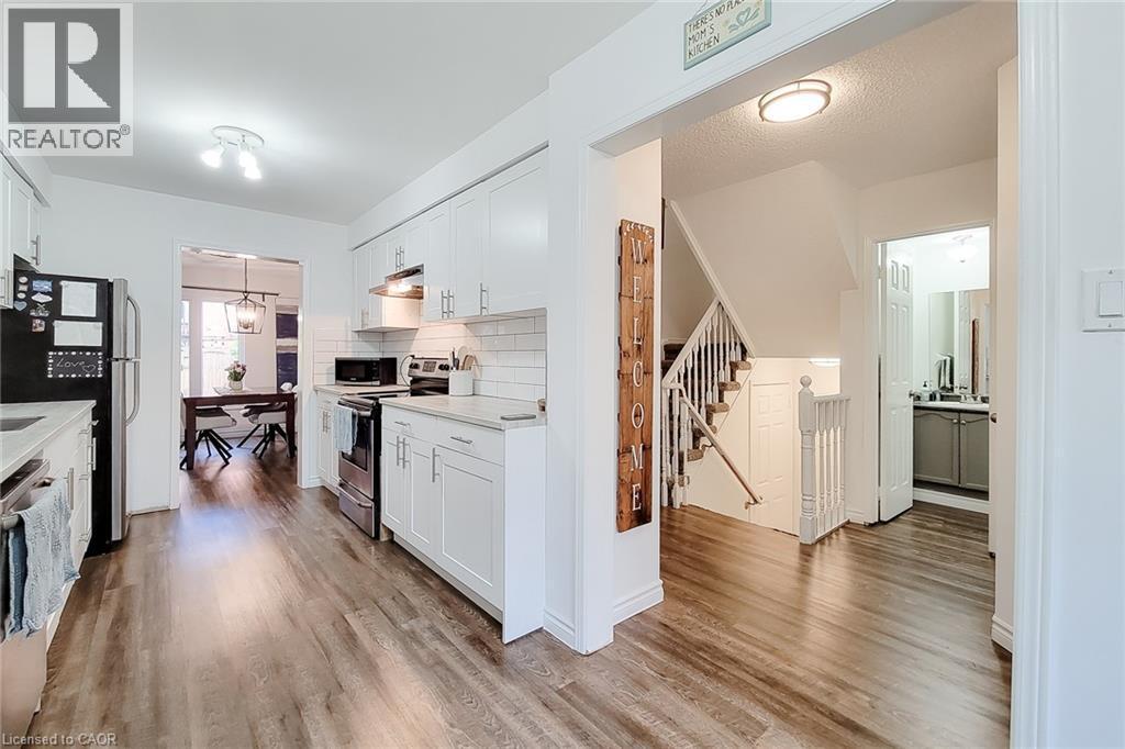 Modern kitchen featuring white shaker cabinetry, stainless steel appliances, light countertops, and a subway tile backsplash - 7 Davidson Boulevard Unit# 14, Dundas, ON - Indoor Photo Showing Kitchen