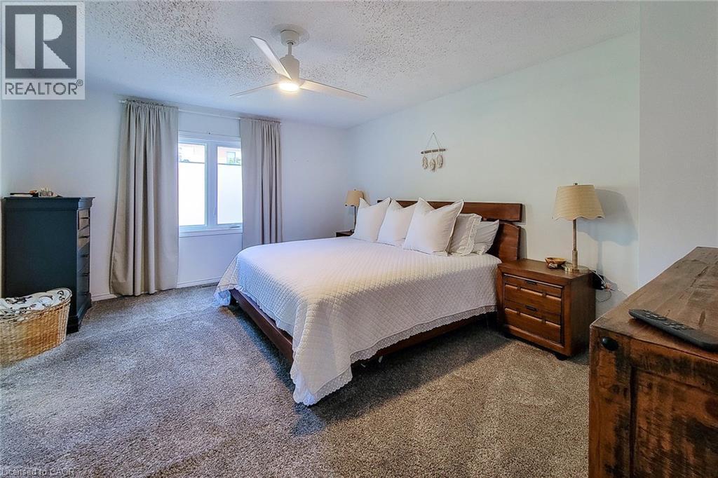 Spacious bedroom featuring plush gray carpeting, a large window with privacy film, a ceiling fan, and ample wall space - 7 Davidson Boulevard Unit# 14, Dundas, ON - Indoor Photo Showing Bedroom