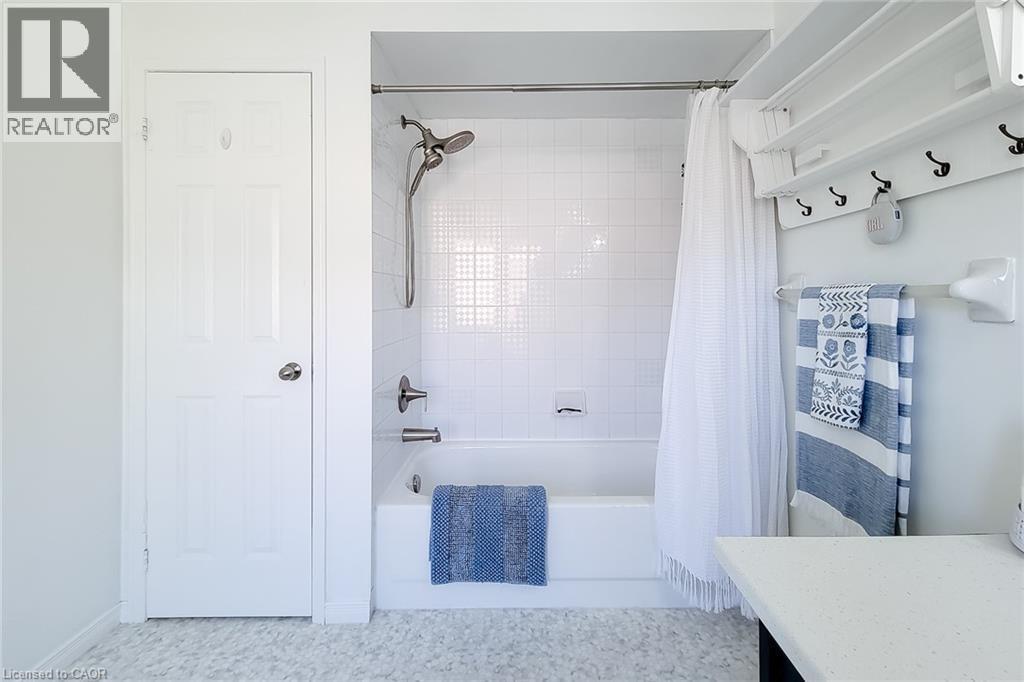 Bathroom featuring a white subway tile tub surround, chrome shower fixtures, and a six-panel door - 7 Davidson Boulevard Unit# 14, Dundas, ON - Indoor