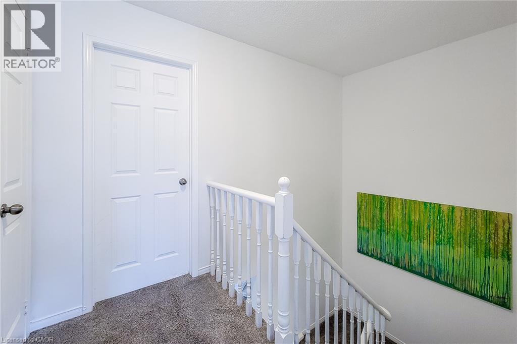 Hallway featuring a six-panel interior door, white baluster railing, and grey carpeting - 7 Davidson Boulevard Unit# 14, Dundas, ON - Indoor Photo Showing Other Room