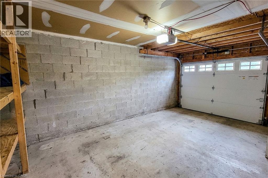 Garage space featuring a concrete floor, exposed joist ceiling, and concrete block walls - 7 Davidson Boulevard Unit# 14, Dundas, ON - Indoor Photo Showing Garage
