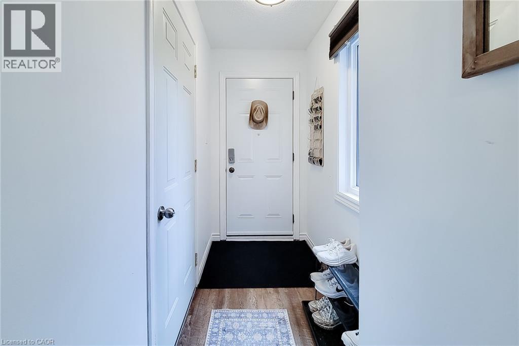 Entryway featuring wood-finish flooring, a white paneled door, and a single window with a dark valence - 7 Davidson Boulevard Unit# 14, Dundas, ON - Indoor Photo Showing Other Room
