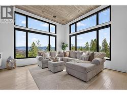 Bright and inviting living room with soaring ceilings, large windows, and a cozy fireplace creating the perfect space to gather and relax. -