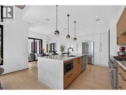 Designed for everyday living and entertaining, the spacious kitchen offers generous prep space, abundant cabinetry, premium appliances, and a large island with bar seating. -