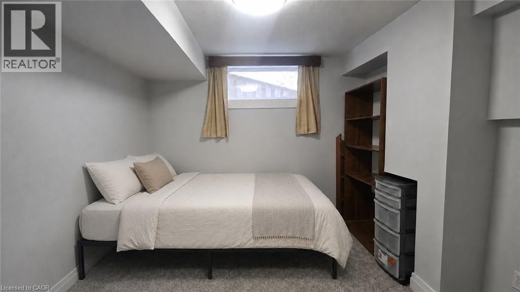 Carpeted room featuring a built-in wooden shelving unit, a single window with natural light, and a flush-mount ceiling light fixture - 10 Doll Court, Kitchener, ON - Indoor Photo Showing Bedroom