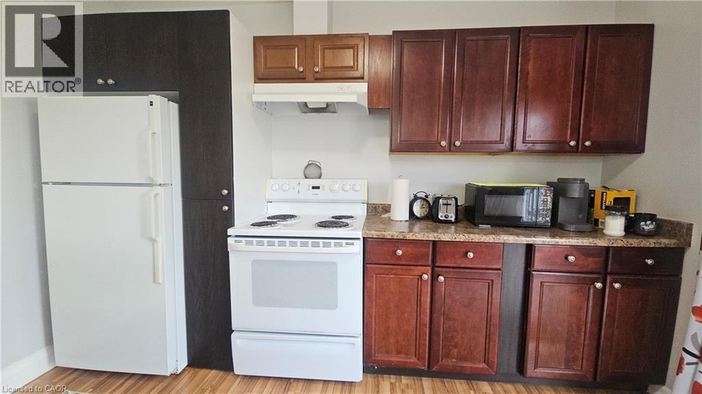 Kitchen featuring wood-finish flooring, dark wood-tone cabinetry, and a light-colored countertop - 10 Doll Court, Kitchener, ON - Indoor Photo Showing Kitchen