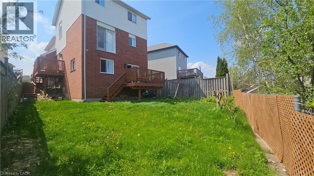 Expansive backyard with a sloped lawn and natural perimeter fencing - 10 Doll Court, Kitchener, ON - Outdoor With Deck Patio Veranda