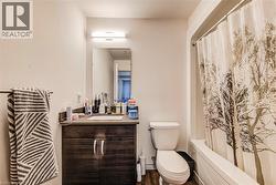 Primary Bathroom featuring a wood-finish vanity with a built-in sink, a wall-mounted mirror, overhead lighting, and a white bathtub -
