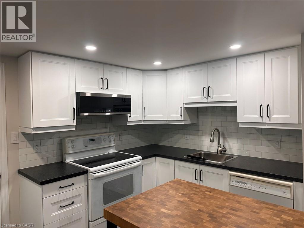 Contemporary kitchen featuring white shaker cabinetry with matte black hardware, dark countertops, and a subway tile backsplash - 4187 Weimar Line, Wellesley, ON - Indoor Photo Showing Kitchen