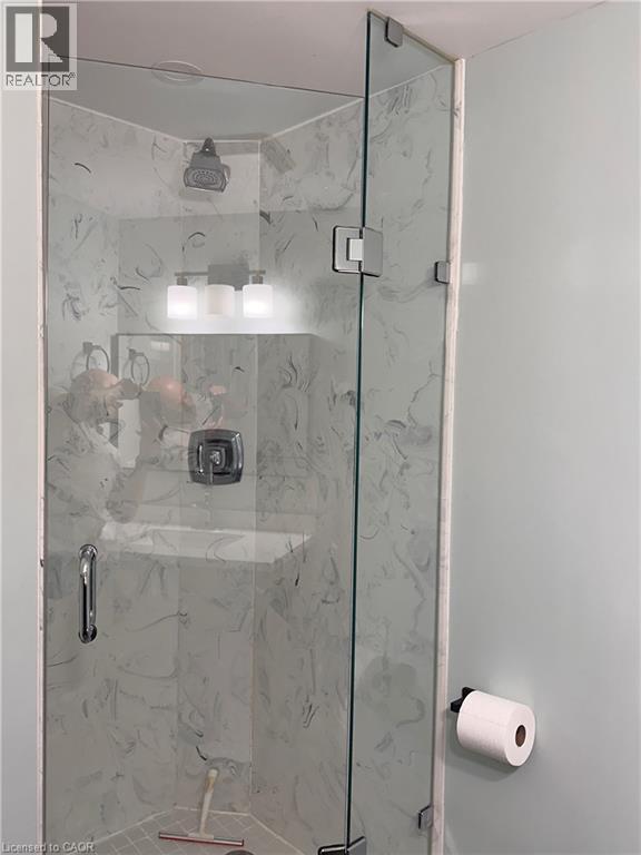 Glass-enclosed shower with a chrome shower head and handle, white marbled-patterned wall panels, and a recessed ceiling light - 4187 Weimar Line, Wellesley, ON - Indoor Photo Showing Bathroom