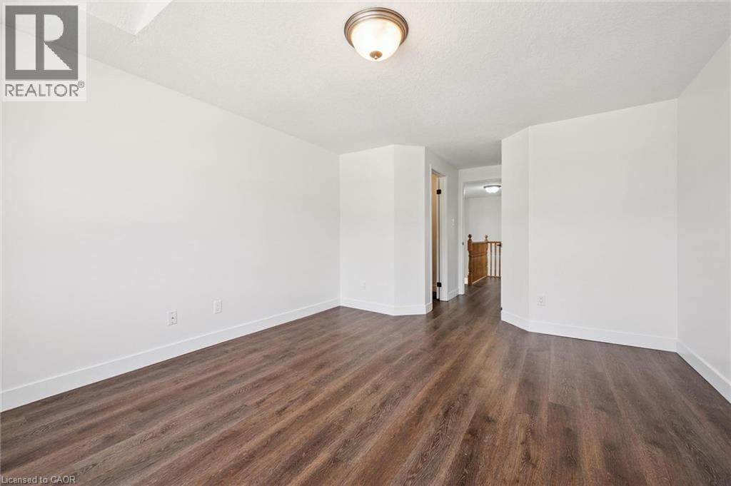 Spacious room featuring wood-finish flooring, white baseboards, and neutral wall paint - 71 Peach Blossom Crescent, Kitchener, ON - Indoor Photo Showing Other Room