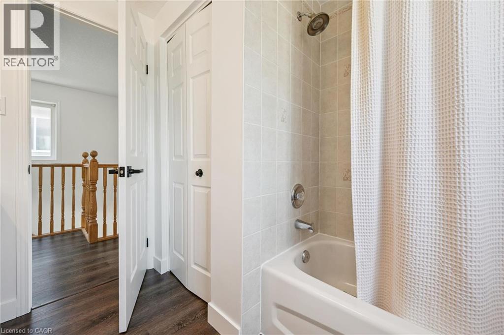Bathroom featuring a white tub, chrome fixtures, and tiled walls - 71 Peach Blossom Crescent, Kitchener, ON - Indoor Photo Showing Bathroom