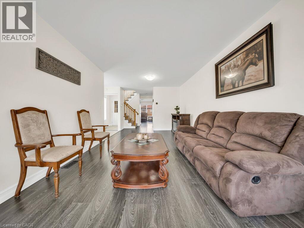 Spacious interior featuring wood-finish flooring, white walls, and a visible staircase with wood newel posts and handrails - 39 Baintree Way, Cambridge, ON - Indoor Photo Showing Living Room