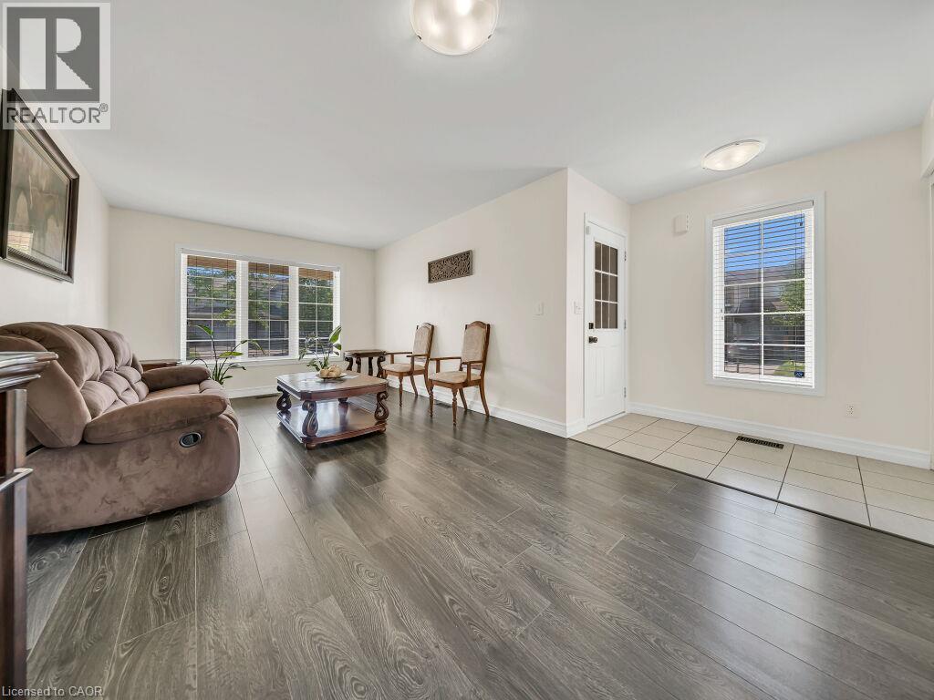 Spacious living area featuring wood-finish flooring, bright white walls, and multiple windows - 39 Baintree Way, Cambridge, ON - Indoor Photo Showing Living Room