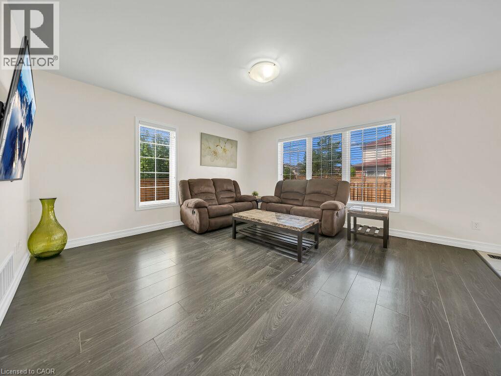 Spacious room featuring wood-finish flooring, white baseboards, and light-colored walls - 39 Baintree Way, Cambridge, ON - Indoor Photo Showing Living Room