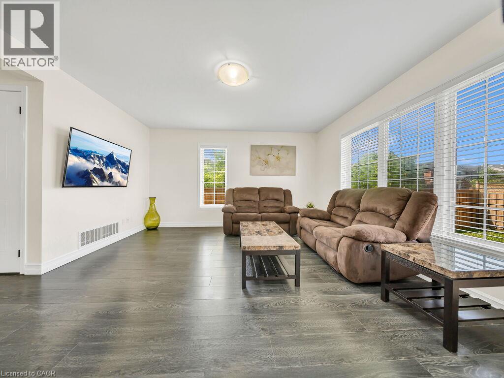 Spacious living area featuring wood-finish flooring, ample natural light from multiple windows, and a neutral color palette - 39 Baintree Way, Cambridge, ON - Indoor Photo Showing Living Room