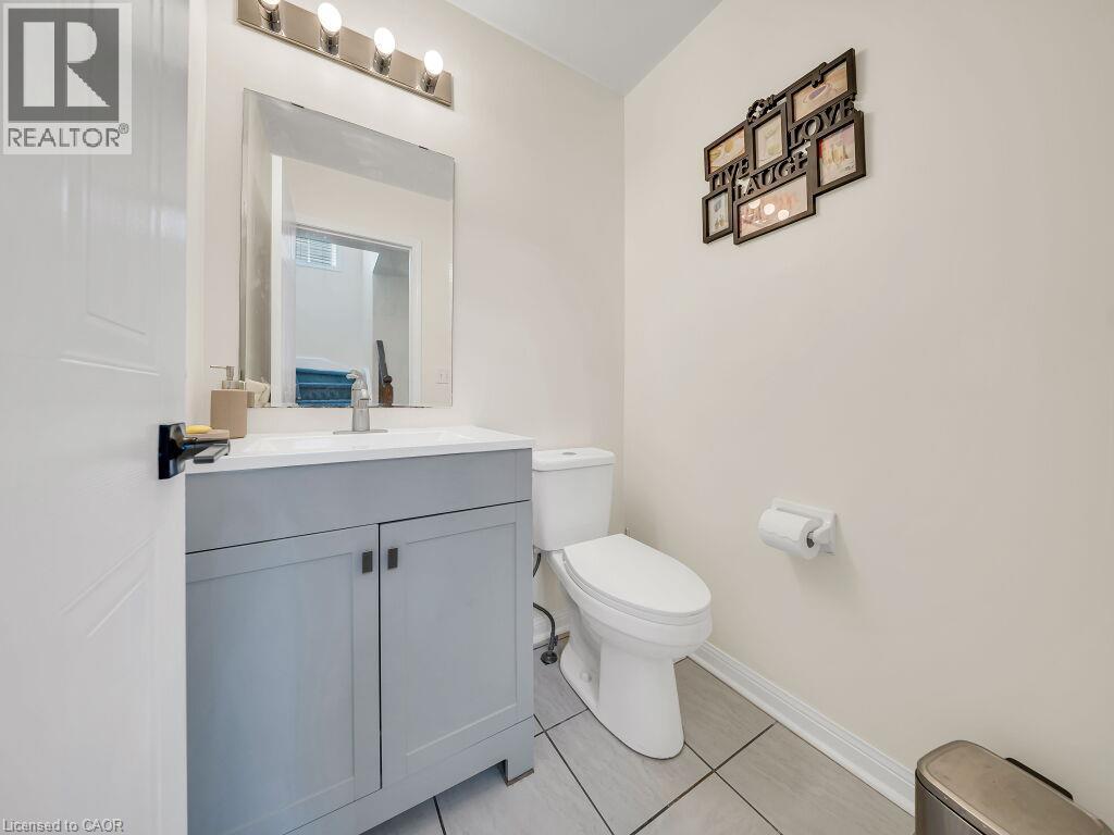 Bathroom featuring a light gray vanity with a white countertop and rectangular sink, a wall-mounted mirror, a four-light fixture, and light-toned floor tiles - 39 Baintree Way, Cambridge, ON - Indoor Photo Showing Bathroom