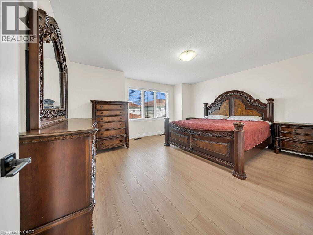 Spacious room featuring light wood-finish flooring, white walls, and a large window with horizontal blinds - 39 Baintree Way, Cambridge, ON - Indoor Photo Showing Bedroom