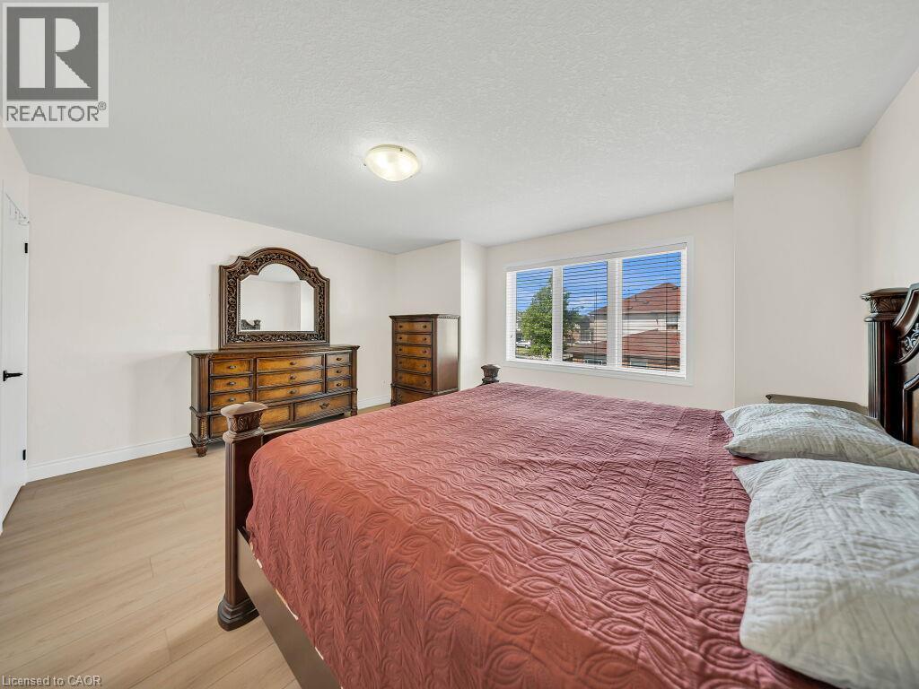 Spacious bedroom featuring light wood-finish flooring, white baseboards, and a neutral wall color - 39 Baintree Way, Cambridge, ON - Indoor Photo Showing Bedroom