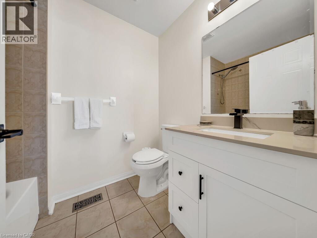 Bathroom featuring a white vanity with a stone-finish countertop, undermount sink, and matte black faucet - 39 Baintree Way, Cambridge, ON - Indoor Photo Showing Bathroom