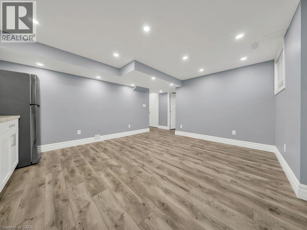 Spacious room featuring wood-finish flooring, light gray walls, recessed ceiling lighting, and white baseboards - 39 Baintree Way, Cambridge, ON - Indoor Photo Showing Other Room