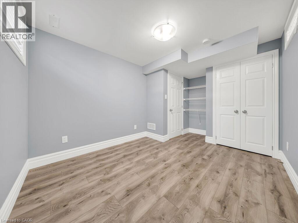 Light gray walls with white baseboards and wood-finish flooring - 39 Baintree Way, Cambridge, ON - Indoor Photo Showing Other Room