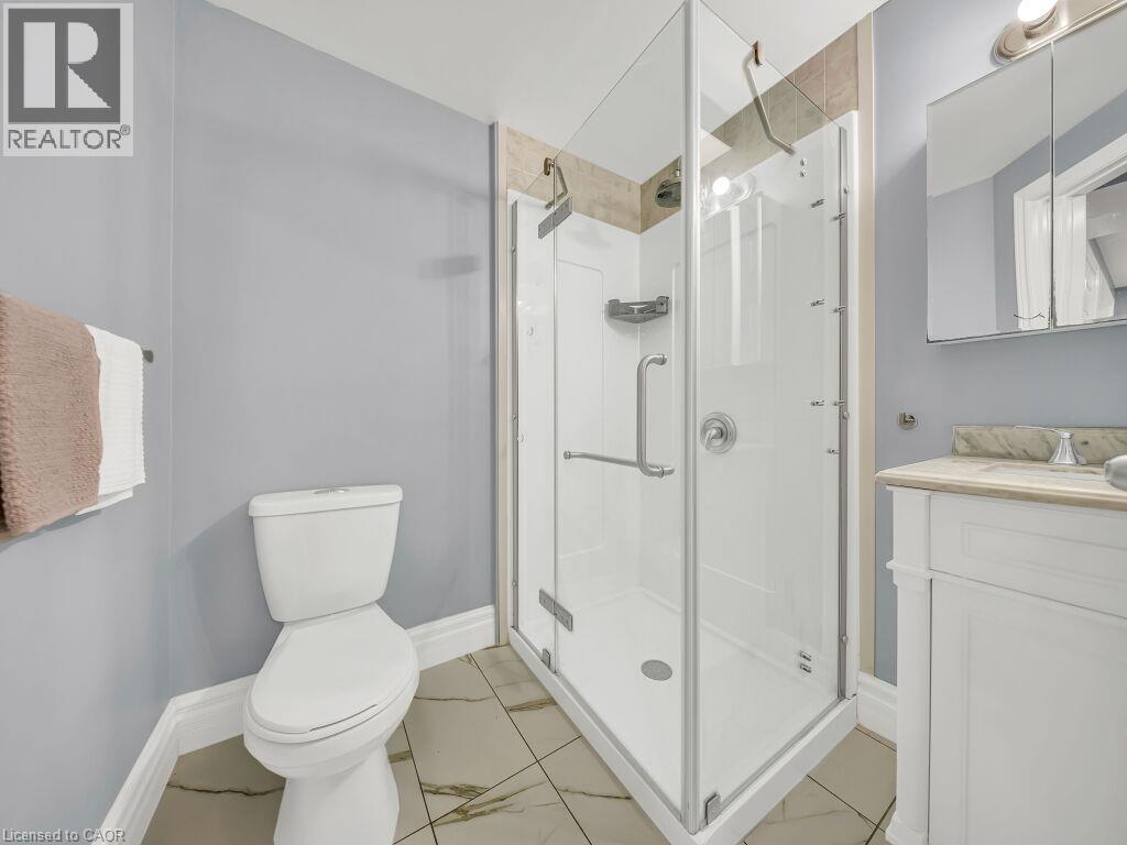 Contemporary bathroom featuring a glass-enclosed shower with a white base, a white vanity with a light-toned countertop, and patterned floor tiling - 39 Baintree Way, Cambridge, ON - Indoor Photo Showing Bathroom