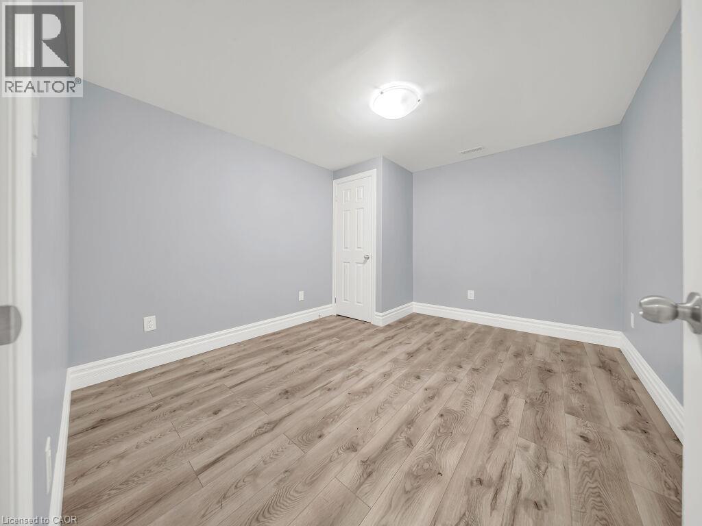 Spacious room featuring wood-finish flooring, light blue wall paint, white trim, and a flush mount ceiling light fixture - 39 Baintree Way, Cambridge, ON - Indoor Photo Showing Other Room