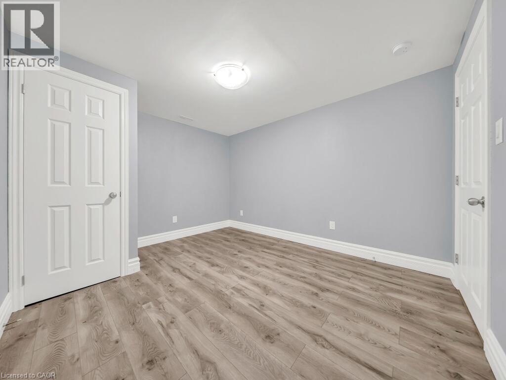 Spacious room featuring wood-finish flooring, light blue walls, white trim, and a flush-mount ceiling light - 39 Baintree Way, Cambridge, ON - Indoor Photo Showing Other Room