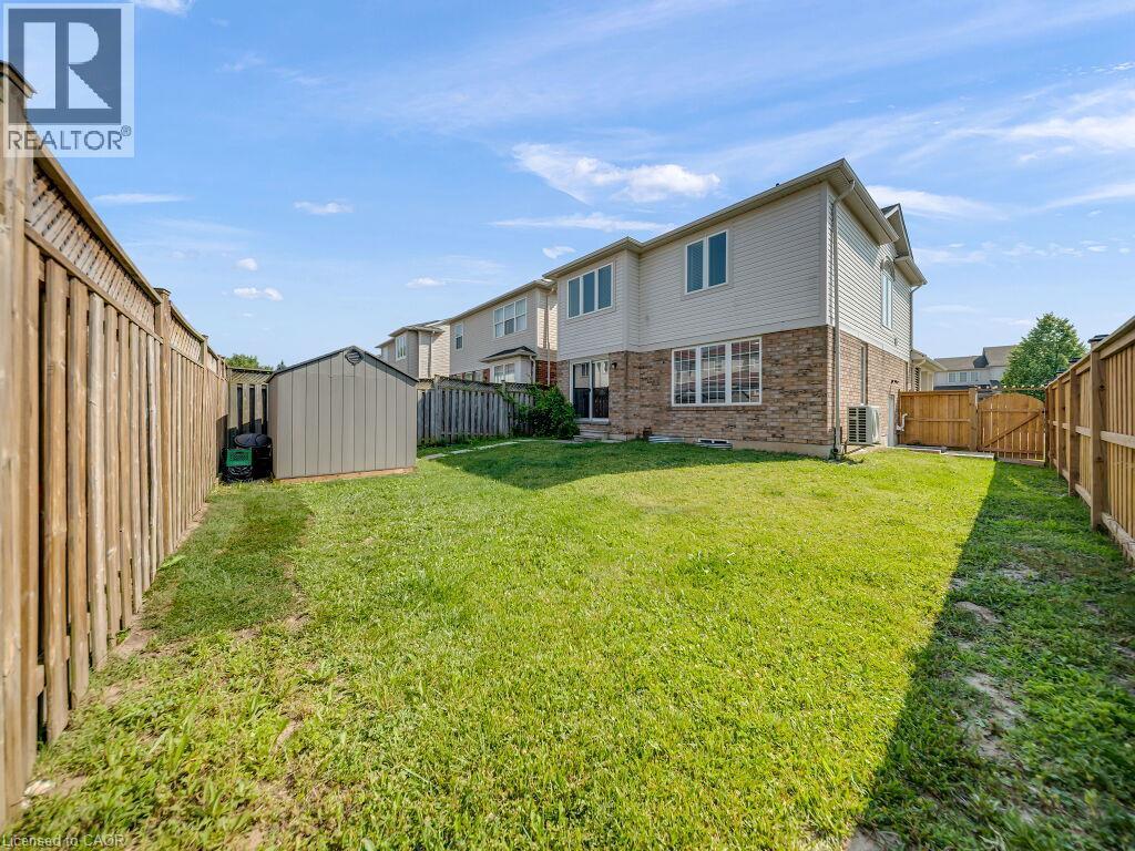 Expansive backyard featuring a manicured lawn, a detached storage shed, and durable wood fencing - 39 Baintree Way, Cambridge, ON - Outdoor