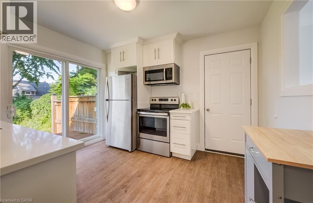 Modern kitchen featuring stainless steel appliances, white cabinetry, and wood-finish flooring - 55 Rex Drive, Kitchener, ON - Indoor Photo Showing Kitchen