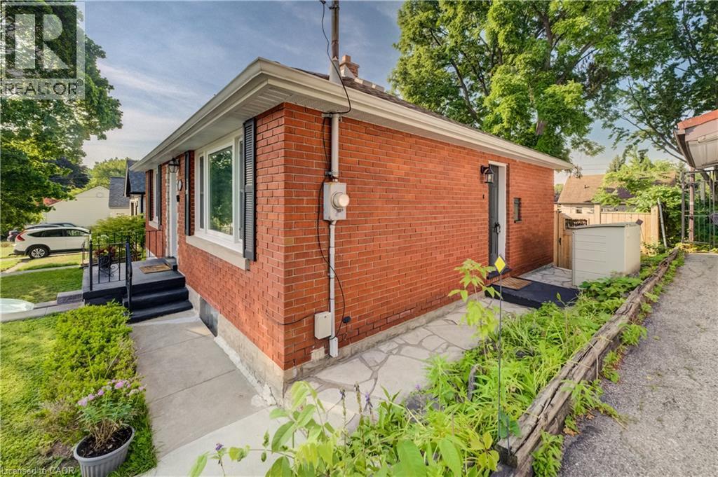 Brick exterior featuring black shutters, a covered front entry, and a side access door - 55 Rex Drive, Kitchener, ON - Outdoor