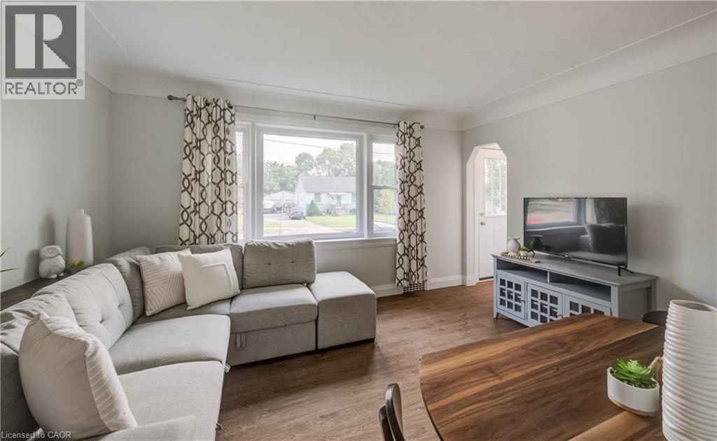 Spacious living area featuring large windows with natural light, wood-finish flooring, light gray walls, and an arched entryway - 55 Rex Drive, Kitchener, ON - Indoor Photo Showing Living Room