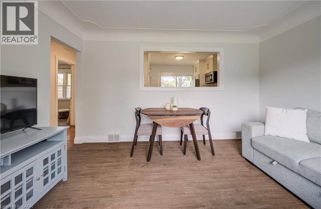 Living area featuring wood-finish flooring, white baseboards, and a pass-through window to the kitchen - 55 Rex Drive, Kitchener, ON - Indoor