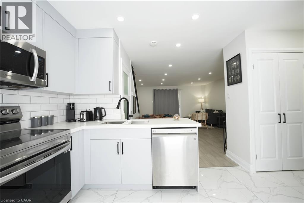 Modern kitchen featuring white cabinetry, subway tile backsplash, stainless steel appliances, and a matte black faucet - 136 Jansen Avenue, Kitchener, ON - Indoor Photo Showing Kitchen With Upgraded Kitchen