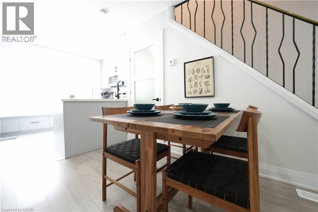 Dining area with light wood-finish flooring, featuring a modern staircase with decorative wrought iron railing - 136 Jansen Avenue, Kitchener, ON - Indoor