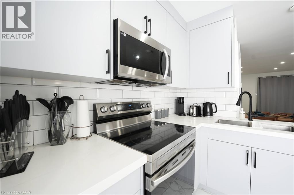 White shaker-style cabinetry with matte black hardware, stainless steel appliances, subway tile backsplash, and a black gooseneck faucet - 136 Jansen Avenue, Kitchener, ON - Indoor Photo Showing Kitchen With Upgraded Kitchen