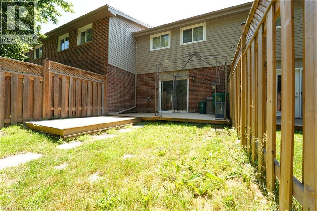 Fenced backyard with a wooden deck, sliding glass doors, and brick exterior - 136 Jansen Avenue, Kitchener, ON - Outdoor With Exterior