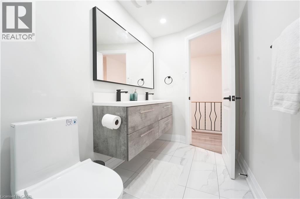 Modern bathroom featuring a floating double vanity with a light gray wood-grain finish, dual vessel sinks, and matte black fixtures - 136 Jansen Avenue, Kitchener, ON - Indoor Photo Showing Bathroom