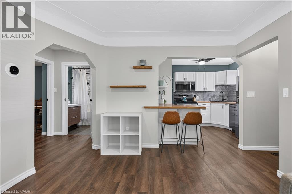 Open-concept living area featuring wood-finish flooring, light gray walls, and white baseboards - 621 Tate Avenue, Hamilton, ON - Indoor Photo Showing Kitchen