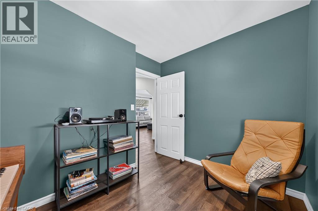 Interior space featuring wood-finish flooring, white baseboards, and a white six-panel door with black hardware - 621 Tate Avenue, Hamilton, ON - Indoor