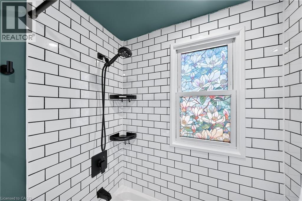 Shower with white subway tile, dark grout, and a decorative frosted window - 621 Tate Avenue, Hamilton, ON - Indoor Photo Showing Bathroom