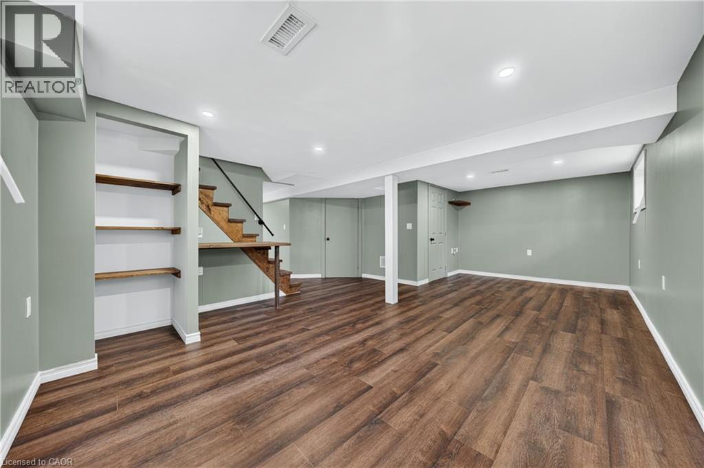 Spacious lower level featuring wood-finish flooring, recessed lighting, and built-in shelving - 621 Tate Avenue, Hamilton, ON - Indoor Photo Showing Other Room